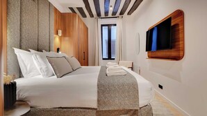 Een moderne hotelkamer met een groot bed, een flatscreen televisie aan de wand en een raam met gordijnen.
