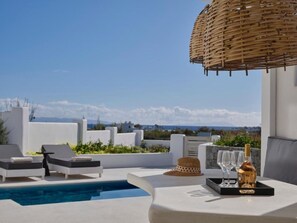 A rooftop terrace with a pool, lounge chairs, a table with a bottle and glasses, and a woven basket overhead. - Maestro East Villa - Villa 2 (Πλάκα)