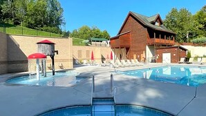 Un espace piscine comprenant un bâtiment en bois, des chaises longues et une fontaine.