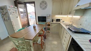 Une cuisine compacte comprenant une table à manger, des chaises, un réfrigérateur, un four à micro-ondes et une cuisinière.