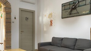 Un salon avec un canapé gris, une table en bois et un climatiseur fixé au mur.