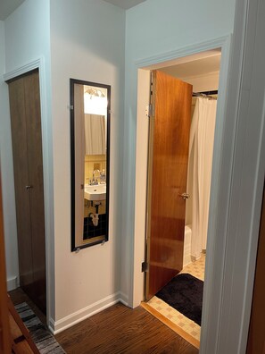 Une salle de bain avec une porte en bois, un miroir et un espace douche.
