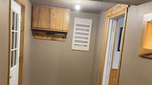 Un passadís amb un armari de fusta, un estri de benvinguda i un cartell amb les normes de la casa.