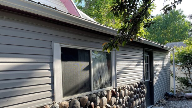 Una casa amb fonaments de pedra i teulada metàl·lica.