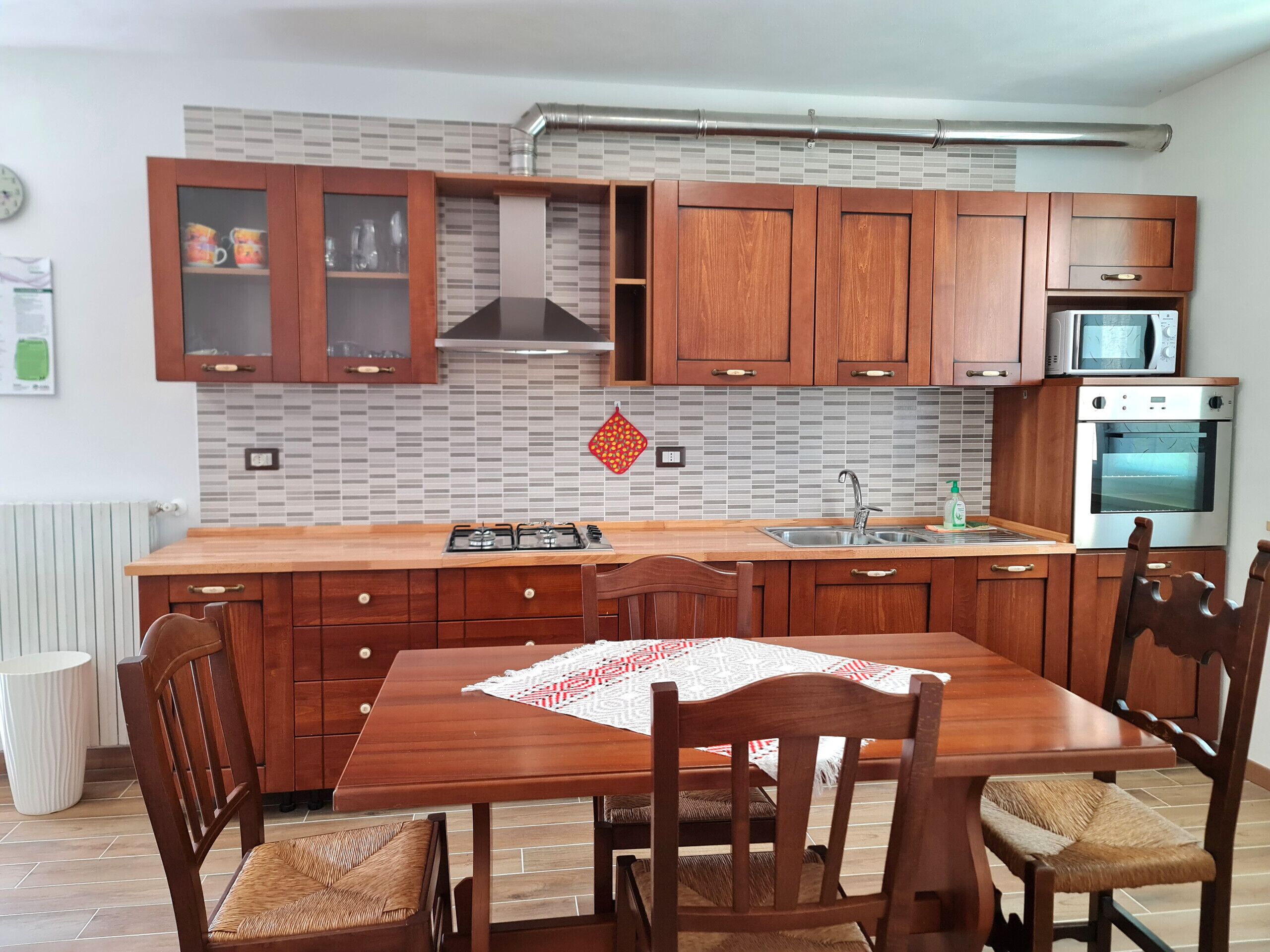Une cuisine moderne avec des meubles en bois, une cuisinière encastrée et un four à micro-ondes.