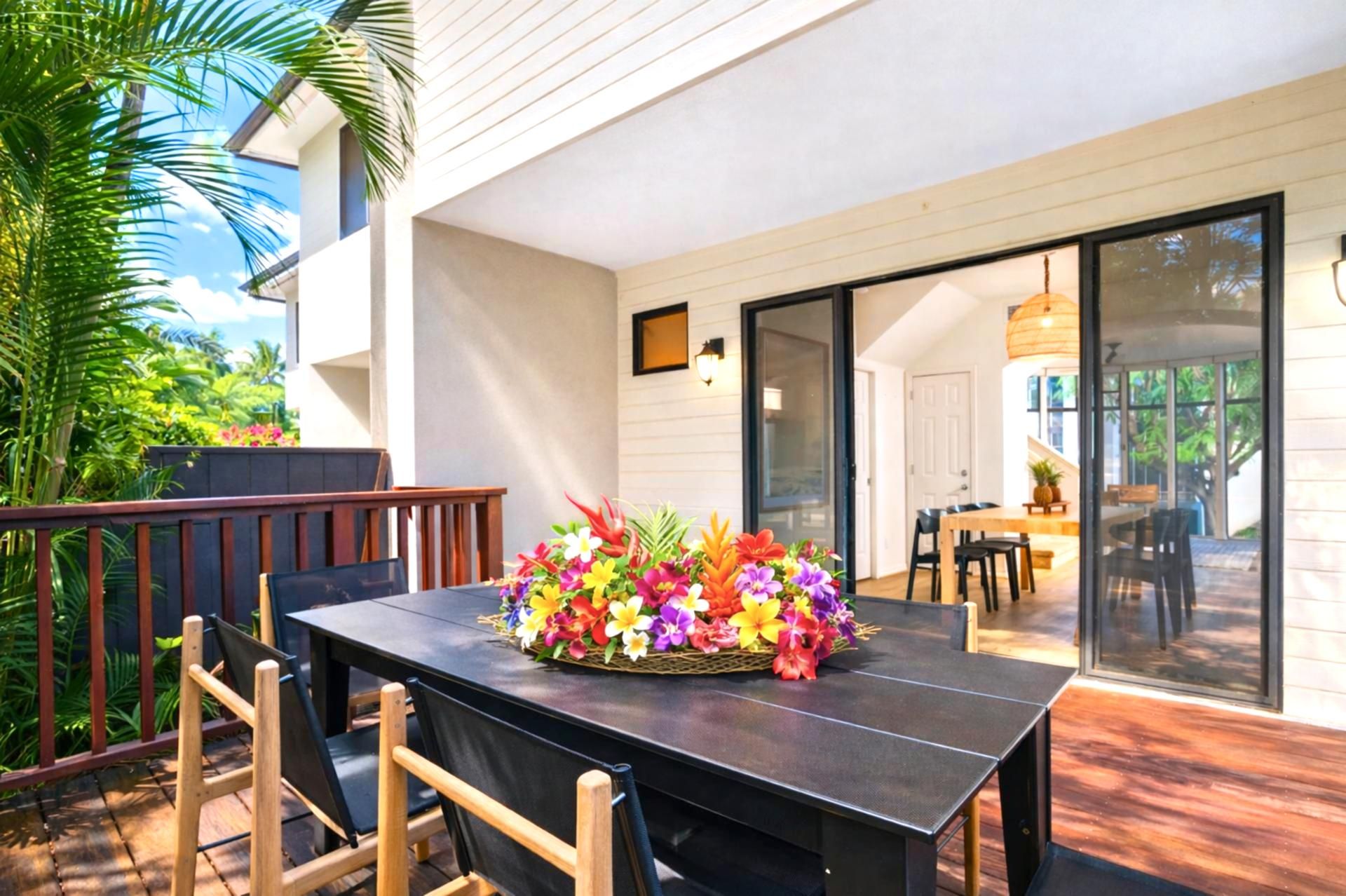 An outdoor dining area with a table set for four, surrounded by chairs, and a large floral arrangement on the table.
