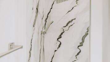 Un baño con ducha y pared de mármol.