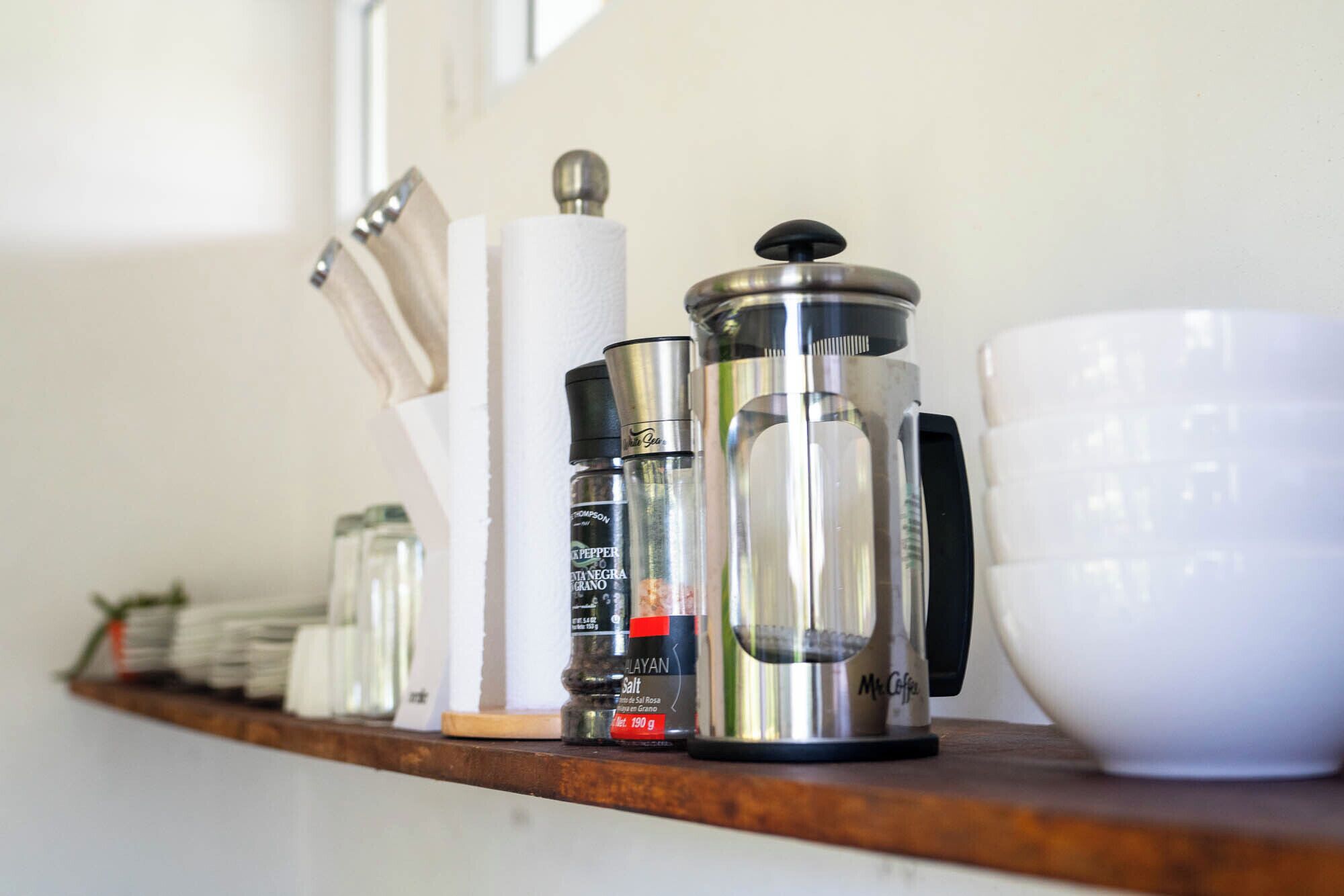 A kitchen shelf with various items including a coffee maker, salt shaker, and a white mug.