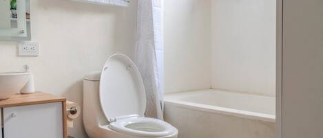 A bathroom with a toilet, sink, and shower area.