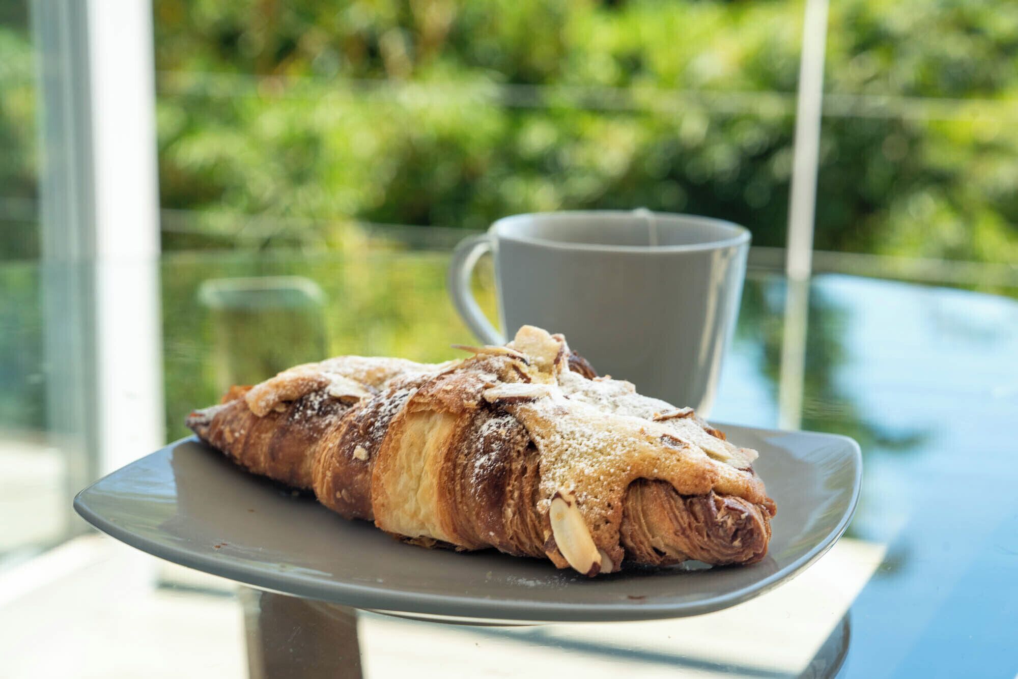 Une pâtisserie sur une assiette, avec une tasse en arrière-plan.