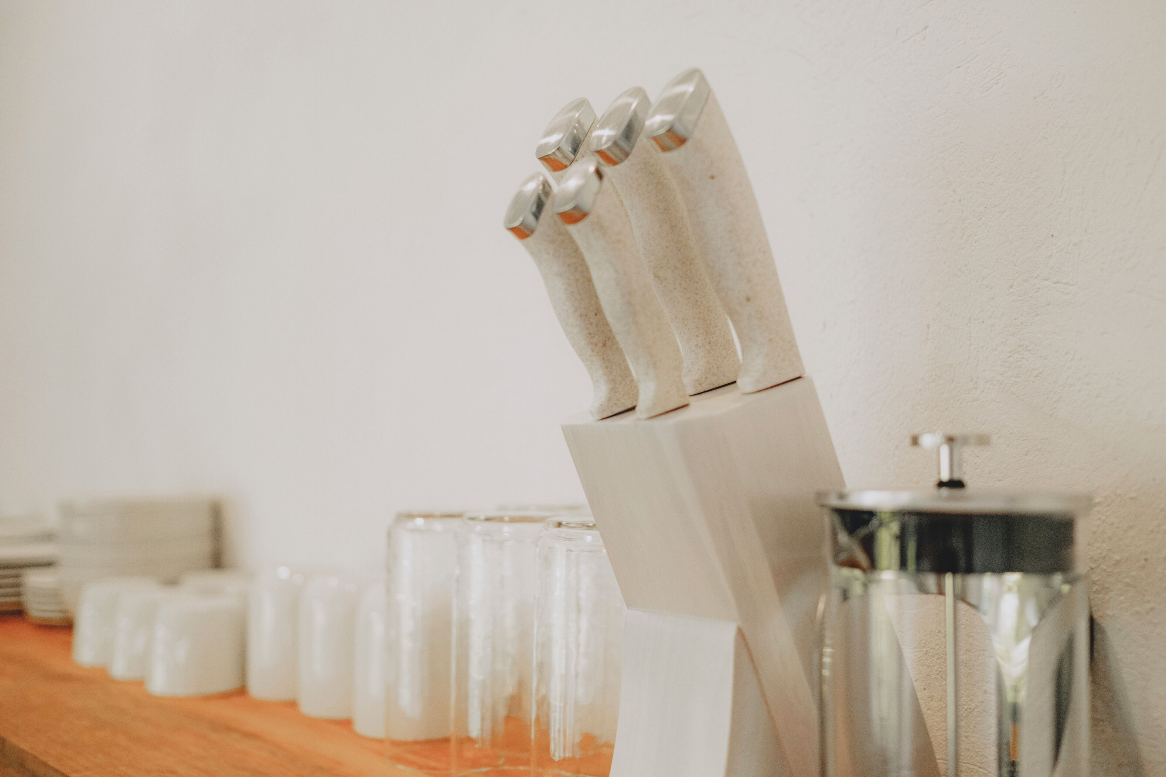 A bar area with a row of glasses and a knife block.