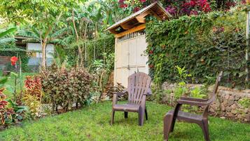 A garden with two wooden chairs, a small wooden structure, and various plants.