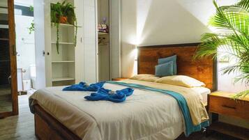 Un dormitorio con cama, mesita de noche, cabecero de madera, armario y una planta en maceta.
