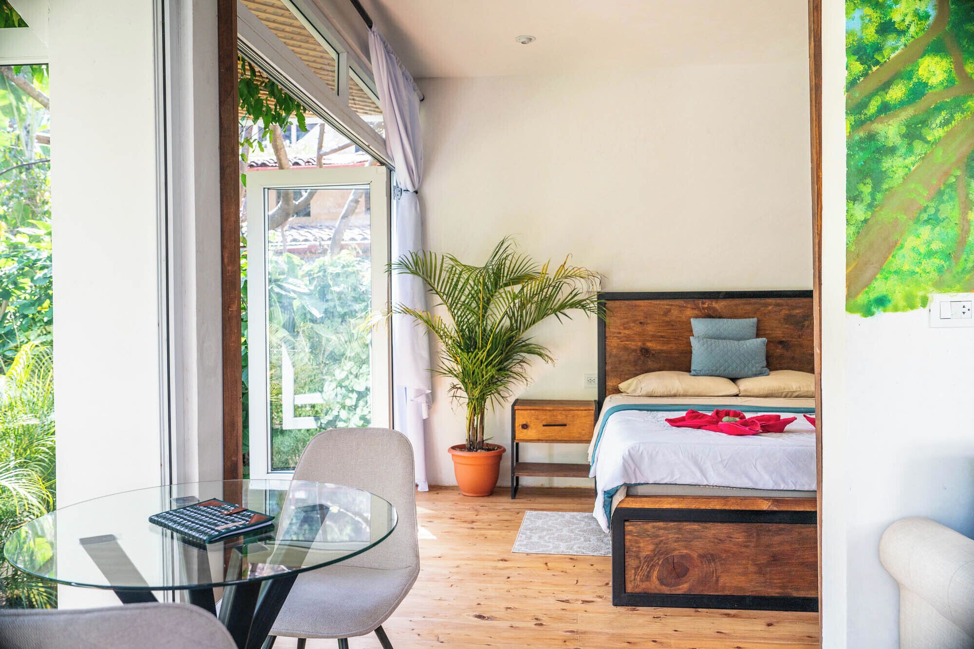 Un dormitorio con cama, mesita de noche, silla y vistas a zonas verdes por una ventana.