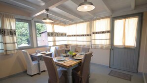 A dining area with a wooden table, chairs, and a ceiling fan. - Accogliente Villa Immersa nel Verde con Incantevole Vista Mare (Sardegna)