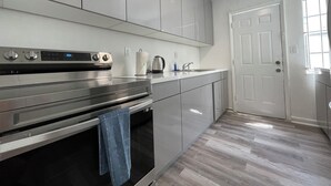 Una cucina moderna con elettrodomestici in acciaio inossidabile, un piano di lavoro bianco e un pavimento in legno.