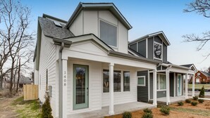 A modern two-story house with a covered porch, a garage, and a small front yard.