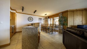 Een ruime keuken met granieten aanrechtbladen, houten kastjes en een eethoek met een grote tafel en stoelen.