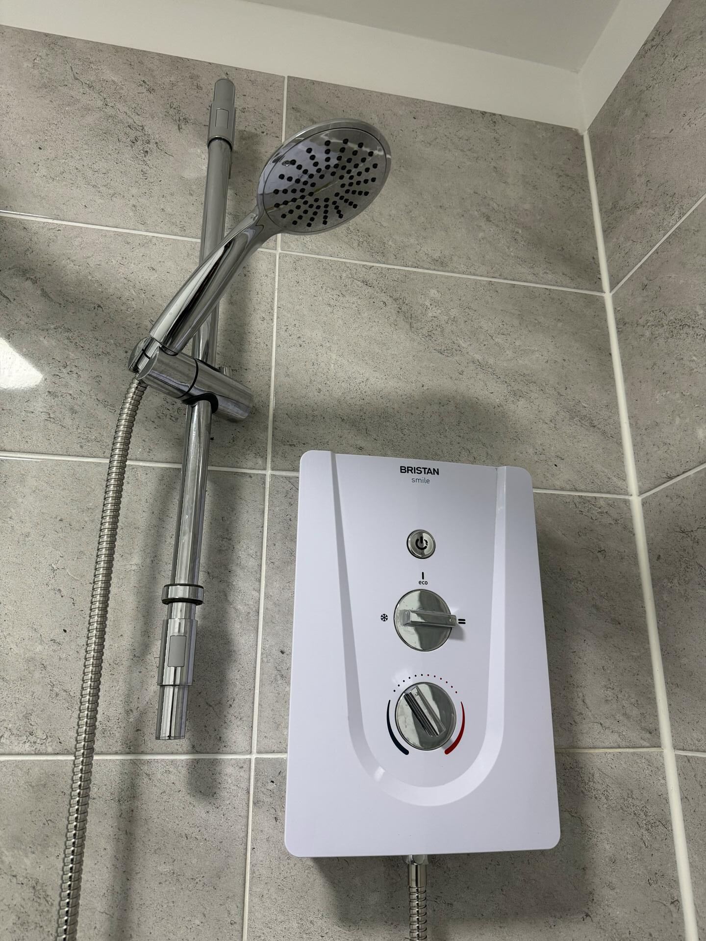 A bathroom with a shower unit and a control panel.