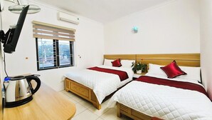 Habitación de hotel con dos camas, un escritorio de madera, un hervidor de agua y una ventana con persianas.