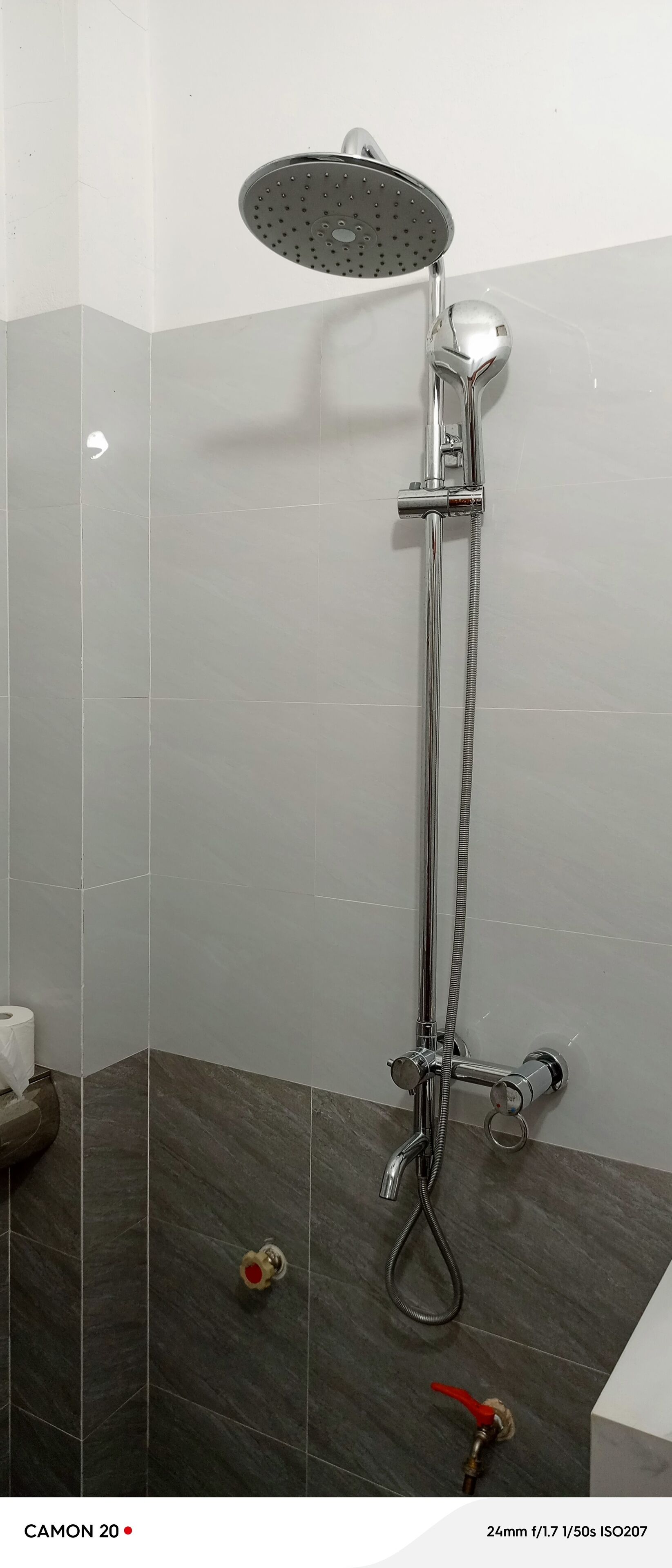 A shower with a handheld showerhead and a wall-mounted faucet.