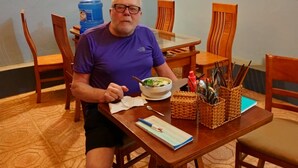 Un comedor con una mesa preparada para una persona, un dispensador de agua y un mapa en la pared.