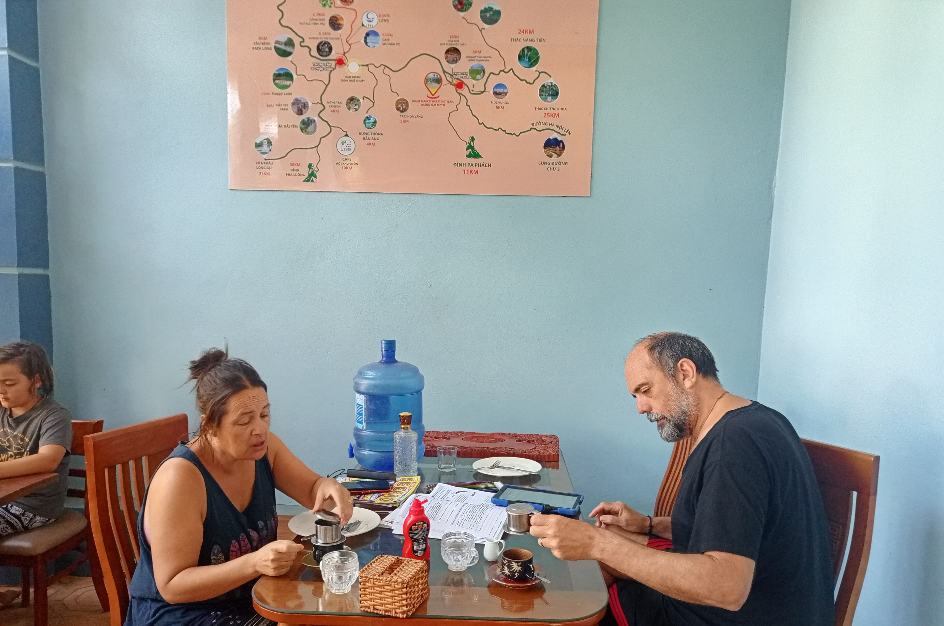 A dining table with a map, a water dispenser, and various food items.