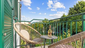 A balcony with wicker chairs, a table, and a bottle of wine. - NAT APARTMENTS Koper - Green All Around - Daisy and Tulip Apartments (Koper)