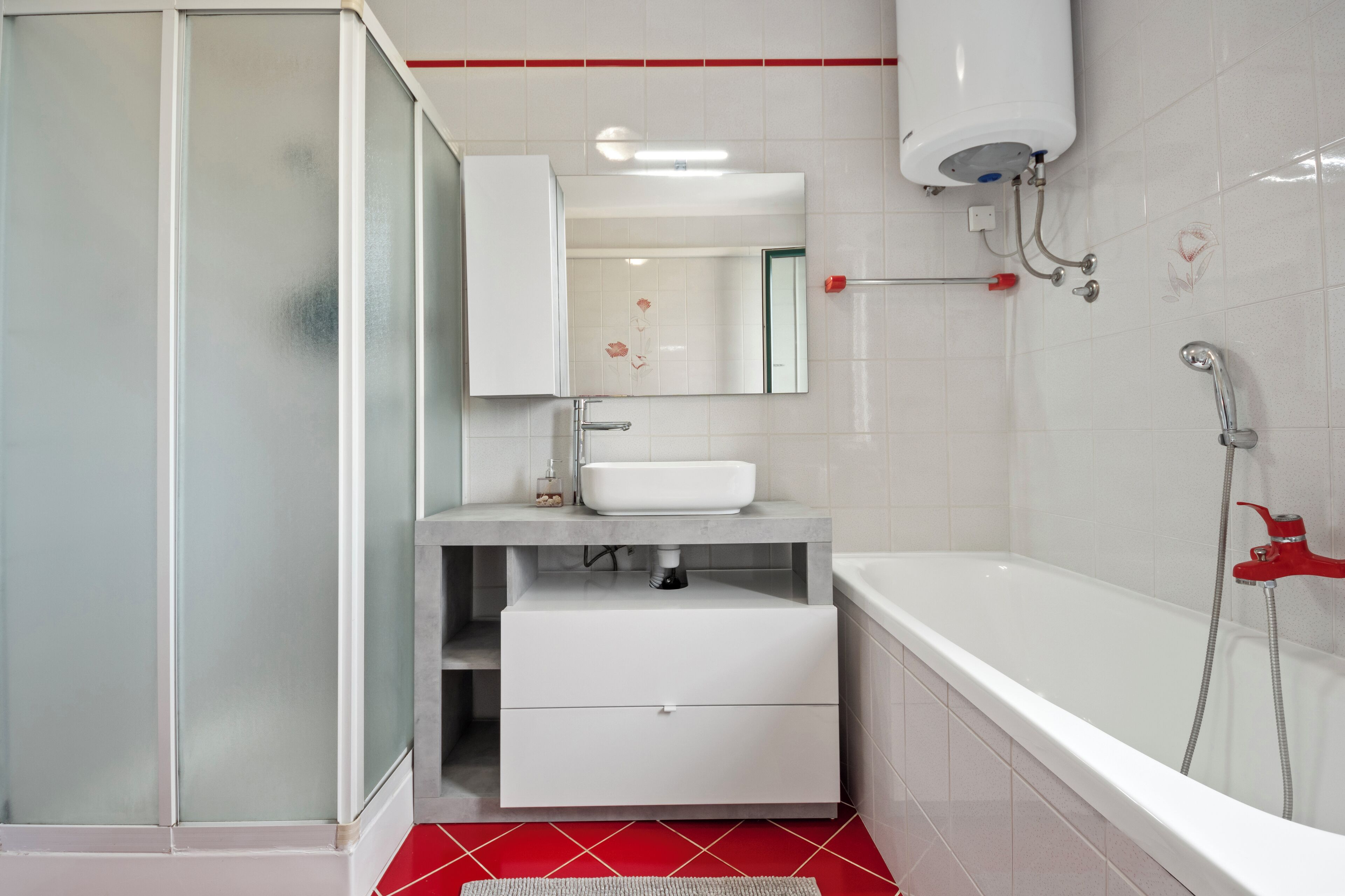 A modern bathroom with a glass shower enclosure, a white sink, and a bathtub.