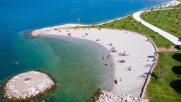A beach with clear blue water, a sandy shore, and a few people. - NAT APARTMENTS Koper - Green All Around - Daisy and Tulip Apartments (Koper)