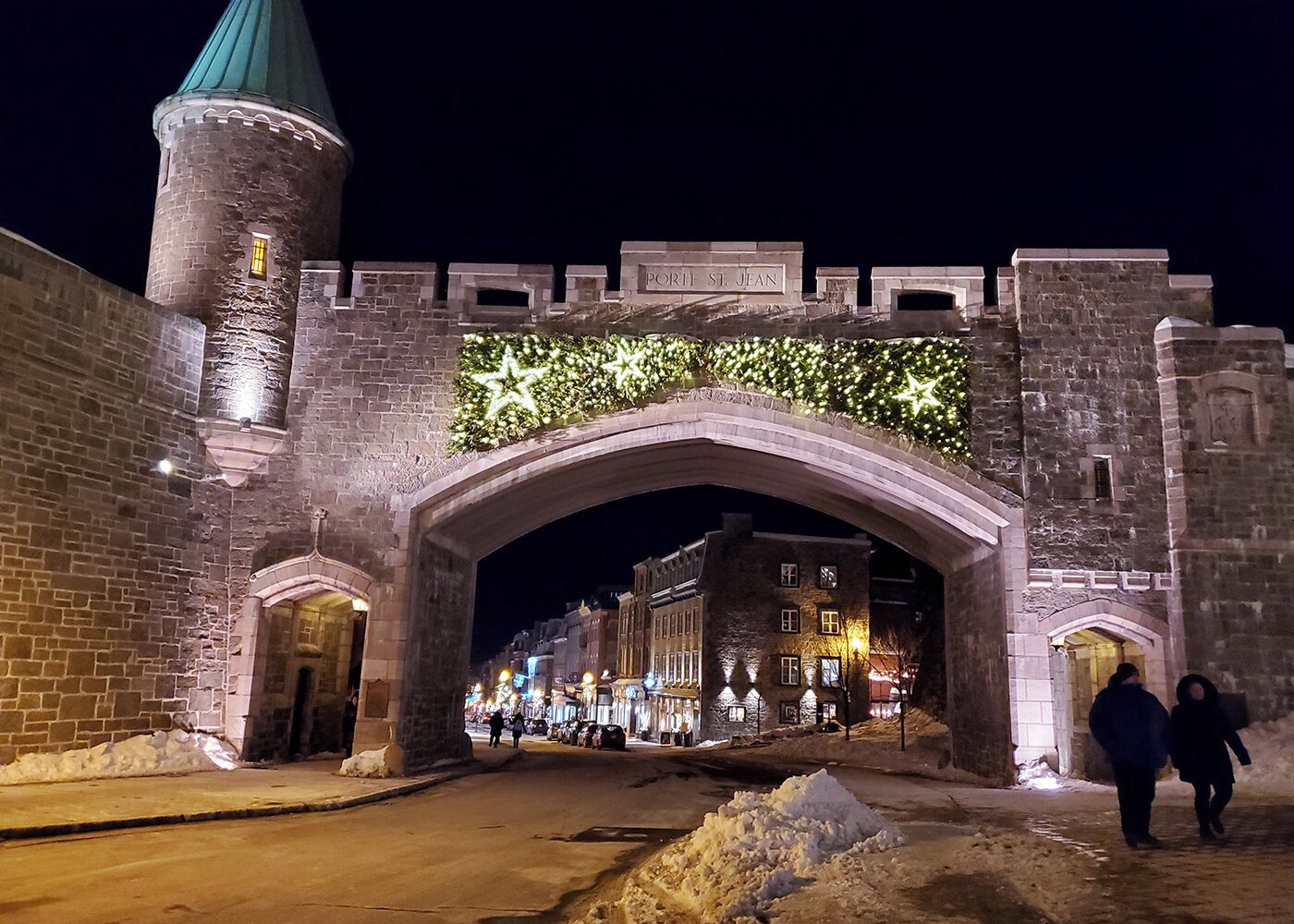A historic stone archway with a sign reading "Portie St. Jean" at night.