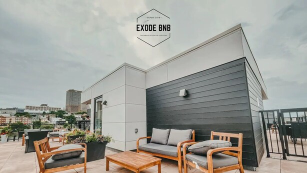 A rooftop terrace with modern furniture, including a sofa and chairs, and a view of the cityscape. - Rustique, NEW in Quebec city - 2 rooms + 2 bathroom (pool on roof during summer) (Québec)