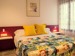 Relax in a cozy retreat with a neatly made bed, bedside tables, and a beautiful piece of artwork.
