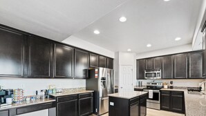 Une cuisine moderne avec des meubles de couleur sombre, des appareils en acier inoxydable et un plan de travail en granit.