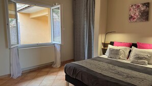 A bedroom with a bed, a window, a radiator, and a painting on the wall.