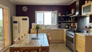 A modern kitchen with a dining table, chairs, a refrigerator, a stove, and a microwave.