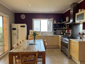 A modern kitchen with a dining table, chairs, a refrigerator, a stove, and a microwave.