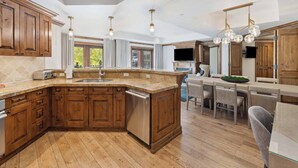 Una cocina amplia con armarios de madera, una isla grande y un comedor con mesa y sillas.