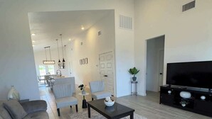 A modern living room with a sofa, coffee table, TV, and ceiling fan. - Family-Friendly Retreat in Canyon Lake (Canyon Lake)