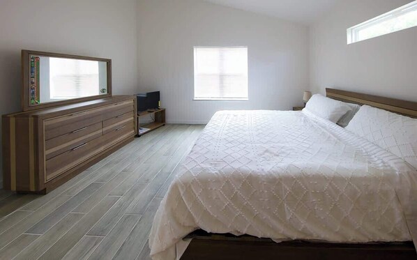 A bedroom with a bed, dresser, TV, and window.