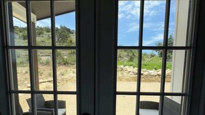 A view through a glass door of an outdoor patio area with wicker furniture and a view of a desert landscape. - Family-Friendly Retreat in Canyon Lake (Canyon Lake)