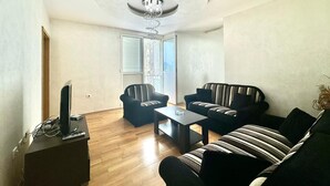 Una sala de estar con techo abovedado, dos sofás, una mesita de centro y un televisor sobre un mueble.