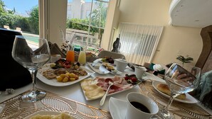 Een ontbijttafel met diverse gerechten, glazen en uitzicht op de omgeving.