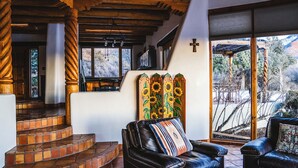 A cozy interior with a leather sofa, a staircase with tiled steps, and a wooden ceiling.