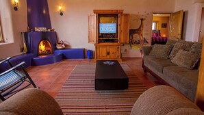 Un salon chaleureux avec une cheminée, un téléviseur et des fauteuils confortables.