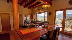 Une cuisine dotée d’un îlot central, de meubles en bois et offrant une vue sur les montagnes grâce à de grandes fenêtres.