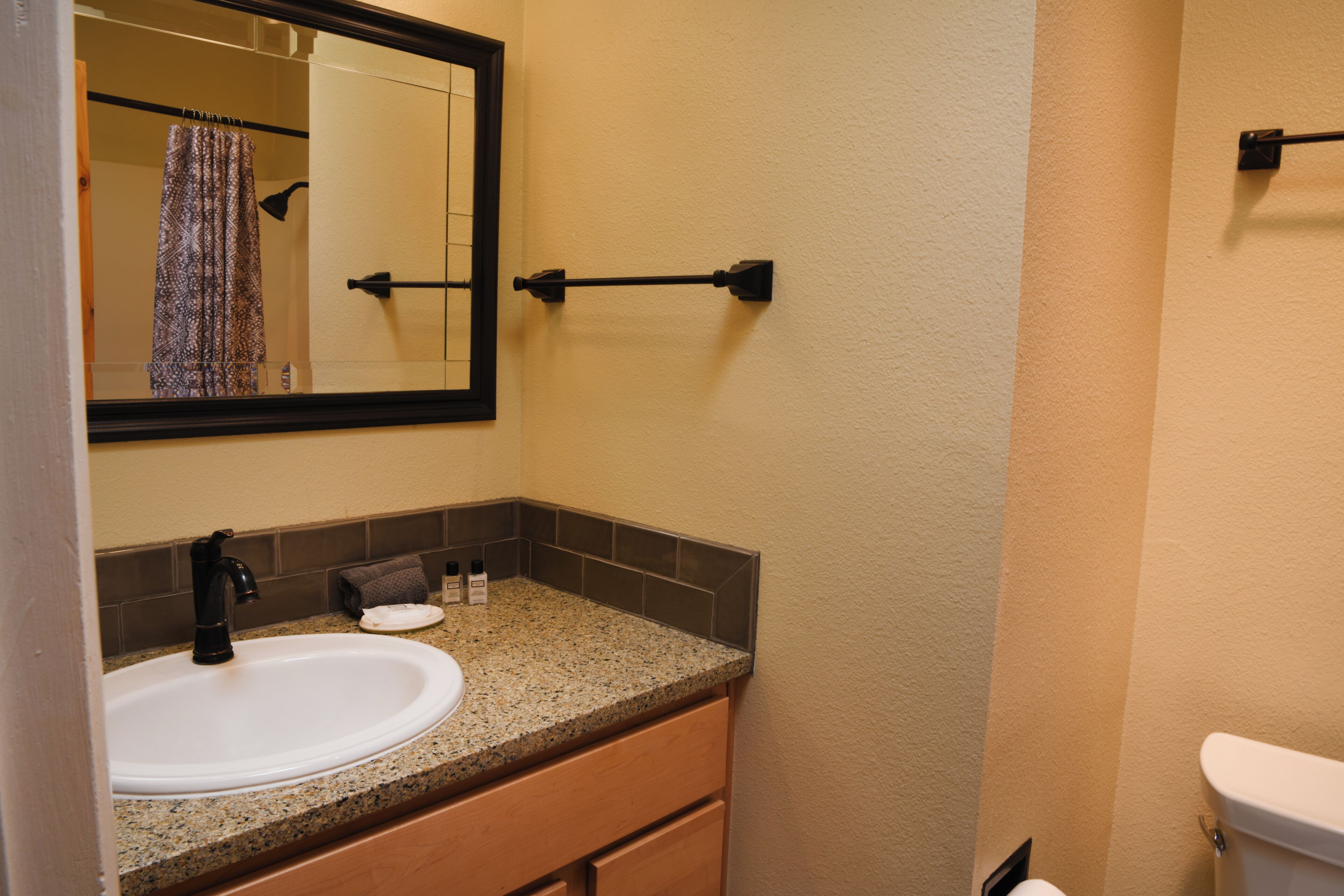 A bathroom with a white sink, a mirror, a towel rack, and a toilet.