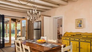 A dining area with a wooden table, white chairs, a chandelier, and a yellow cabinet. - Casitas Encantadas - Charming home with Hot Tub in Taos (Taos)
