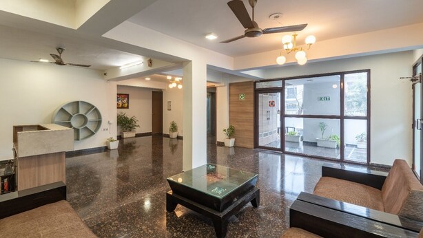 A spacious lobby with a reception desk, seating area, and a glass coffee table. - The Gleam Hotel (Gurugram)