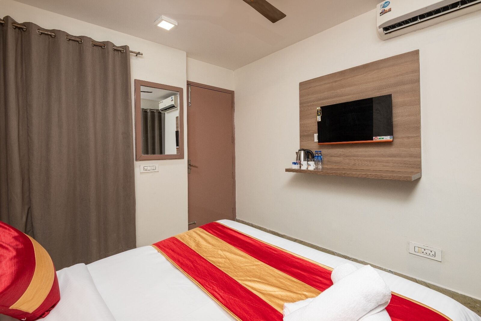 Ein Hotelzimmer mit einem Bett, einem Spiegel, einer Klimaanlage und einem Ablagefach mit Toilettenartikeln.